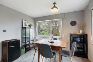 A compact kitchen with a dining table, chairs, a refrigerator, a microwave, and a clock on the wall. - Apartment 'Wanderer Lodge Am Breitenstein' with Private Garden and Wi-Fi (Bissingen an der Teck)