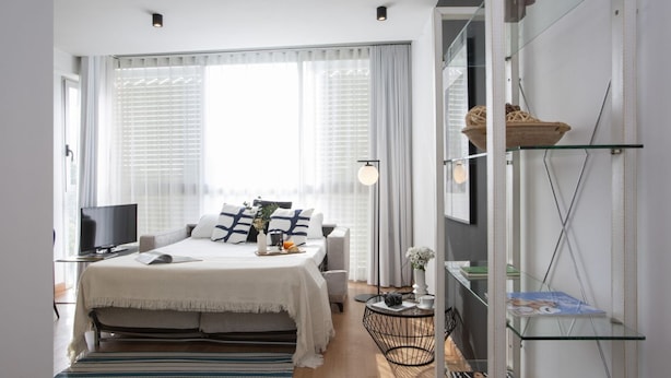 A modern bedroom with a bed, a TV, a bedside table, a lamp, and a window with curtains. - La Pergola 3B - Double Studio Exterior (Castellón)