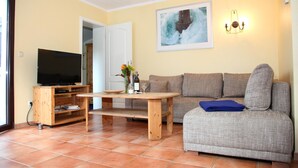 A living room with a television, a wooden table, a sofa, and a painting on the wall.