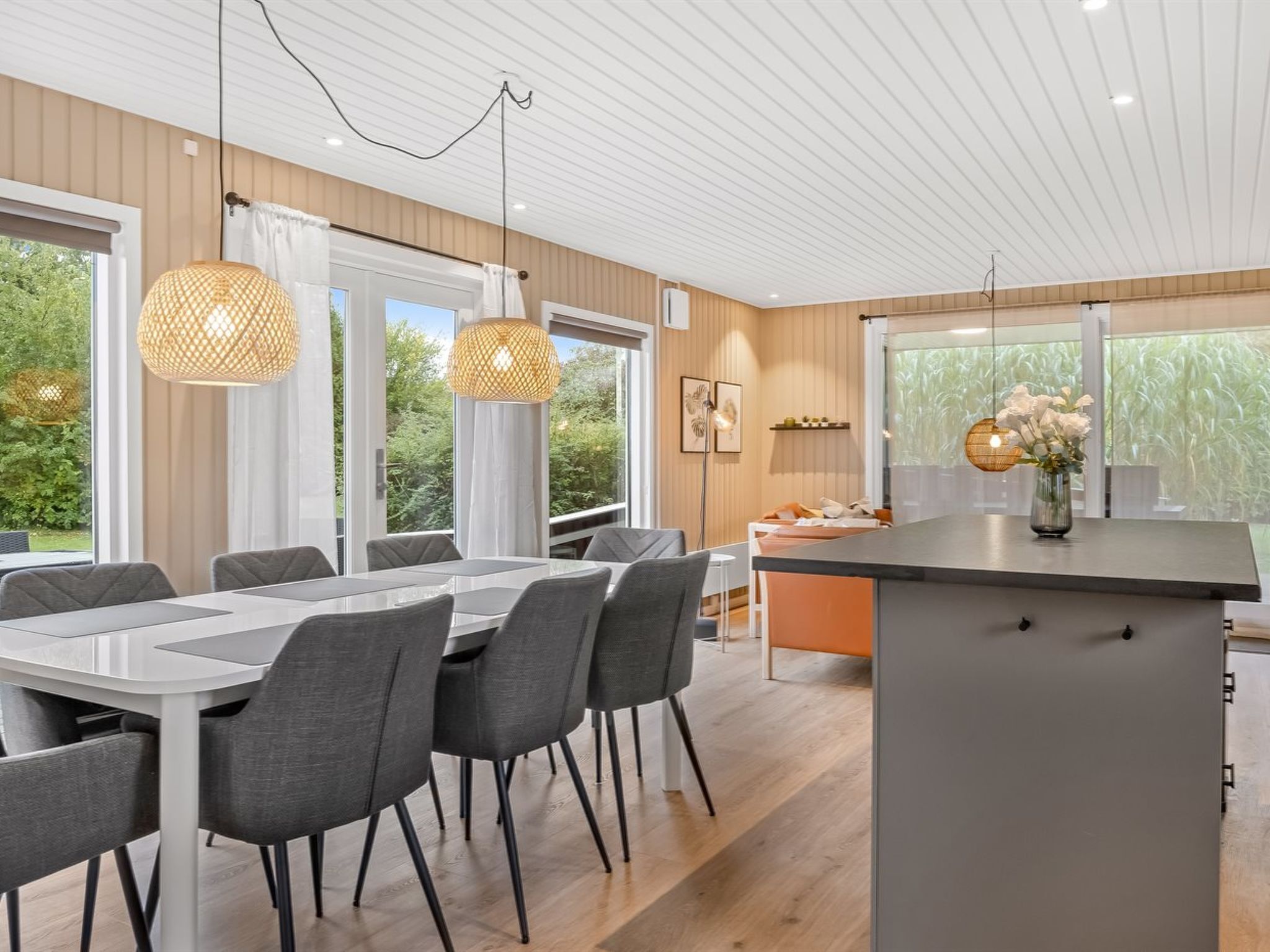 A modern kitchen with a central island, large windows, and pendant lighting.