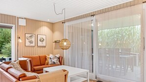A modern living room with a sofa, coffee table, and a view of an outdoor deck. - "Lymke" - 450m from the sea by Interhome (Sydals)