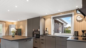 A modern kitchen with grey cabinets, a central island, a built-in oven, and a window overlooking a garden. - "Lymke" - 450m from the sea by Interhome (Sydals)