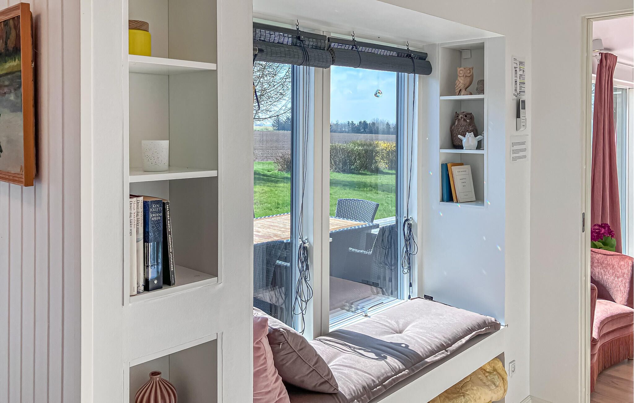 Una habitació amb seients integrats a la finestra, prestatges amb llibres, una taula petita i una cadira.