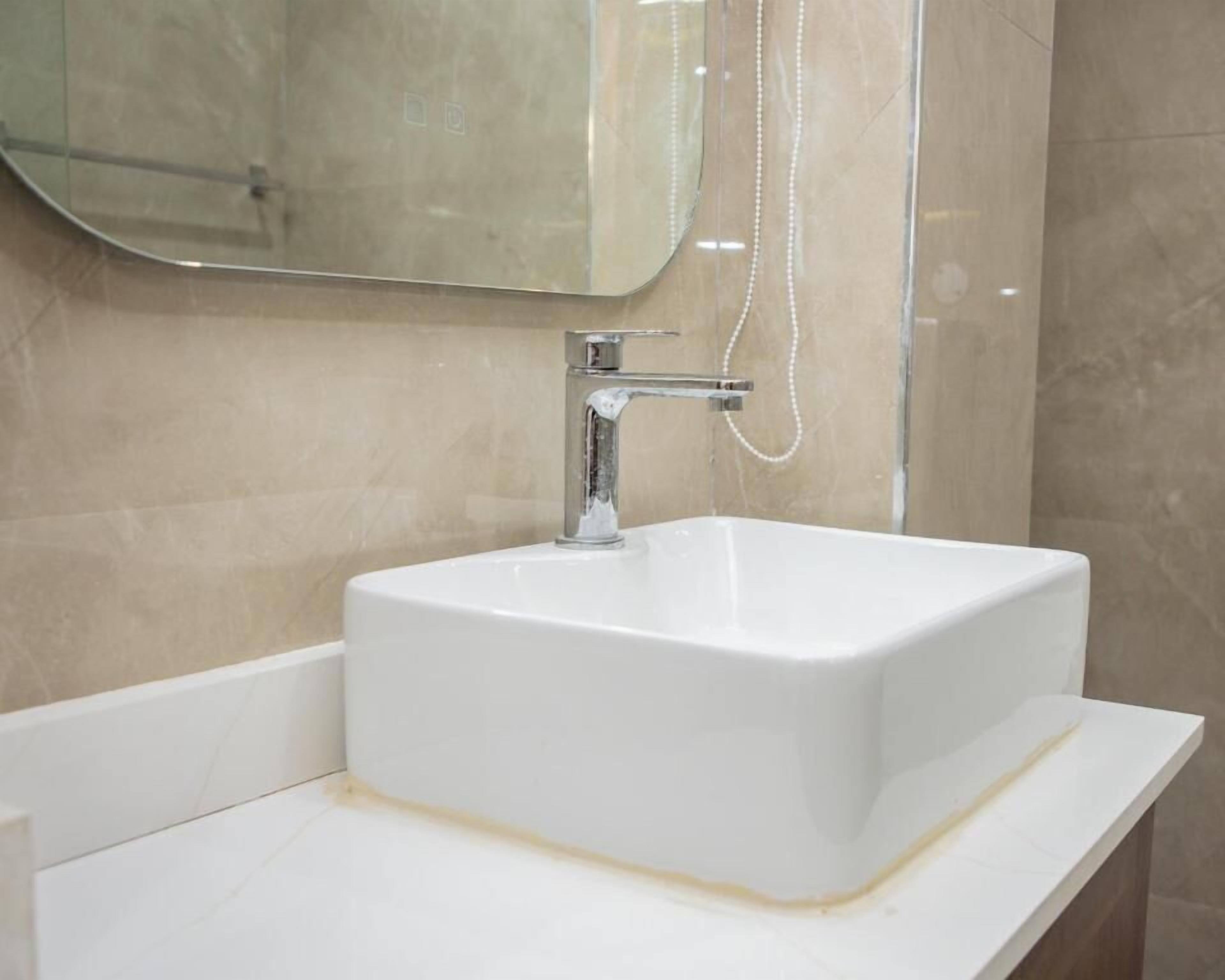 Une salle de bain avec un lavabo blanc, un robinet chromé et une douchette à main.