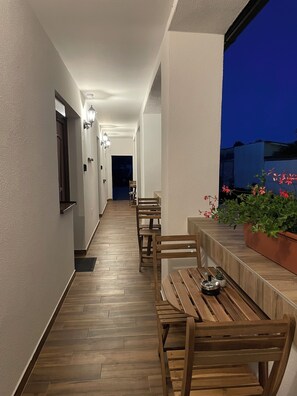 A corridor with wooden benches and a potted plant. - Luna Vendégház (Székesfehérvár)