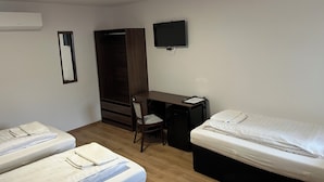 A hotel room with two beds, a desk, a chair, a TV, and a wardrobe. - Luna Vendégház (Székesfehérvár)