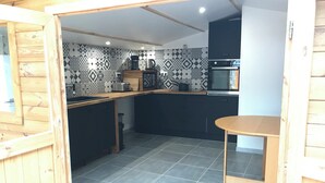 A modern kitchen with black cabinets, a wooden countertop, a built-in oven, and patterned backsplash tiles.