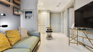 Un salon moderne avec un canapé, une petite table ronde et un téléviseur posé sur un meuble.