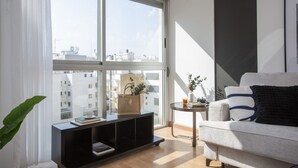 A modern living room with a large window, a sofa, a small side table, and a black entertainment unit. - La Pergola 3F - Double Studio Exterior (Castellón)