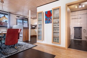 A modern interior with a dining area, kitchen, and wine display.