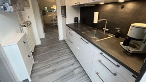 Una cocina moderna con armarios blancos, una encimera negra y una cafetera.