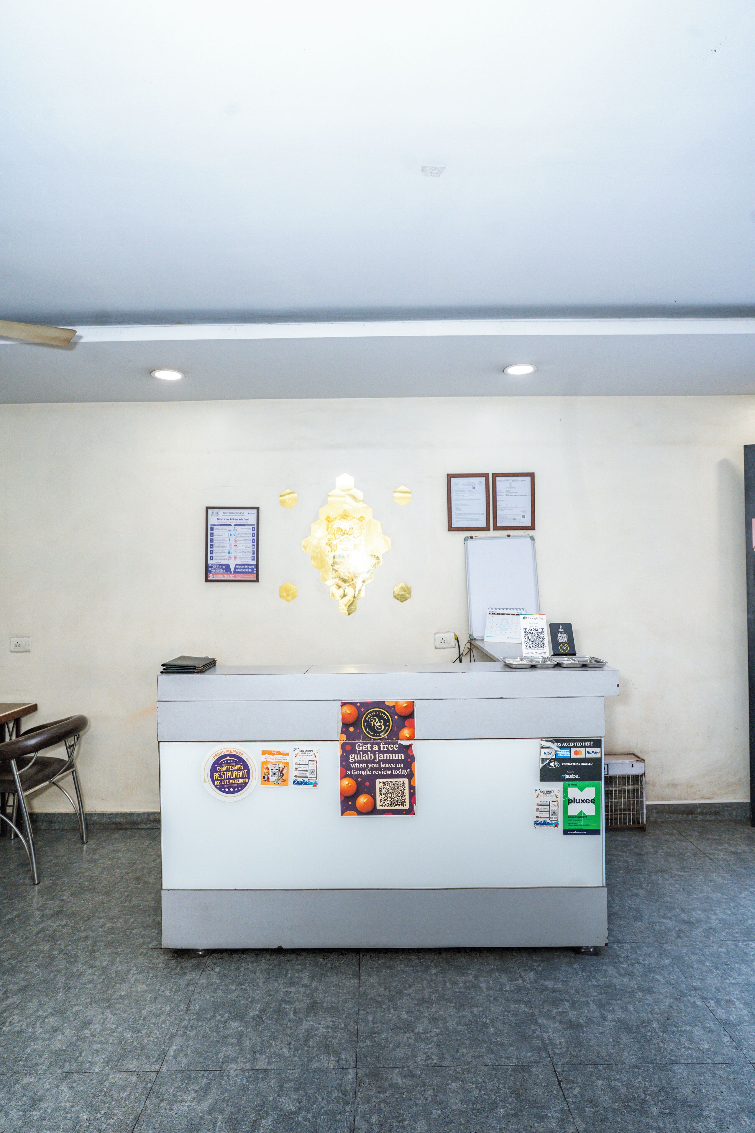 A reception desk with a white counter, a whiteboard, framed certificates, and a QR code for a loyalty program.