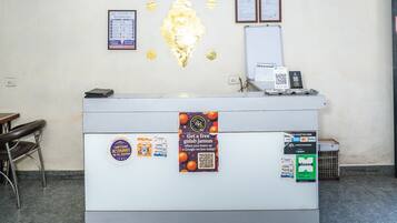 A reception desk with a white counter, a whiteboard, framed certificates, and a QR code for a loyalty program.