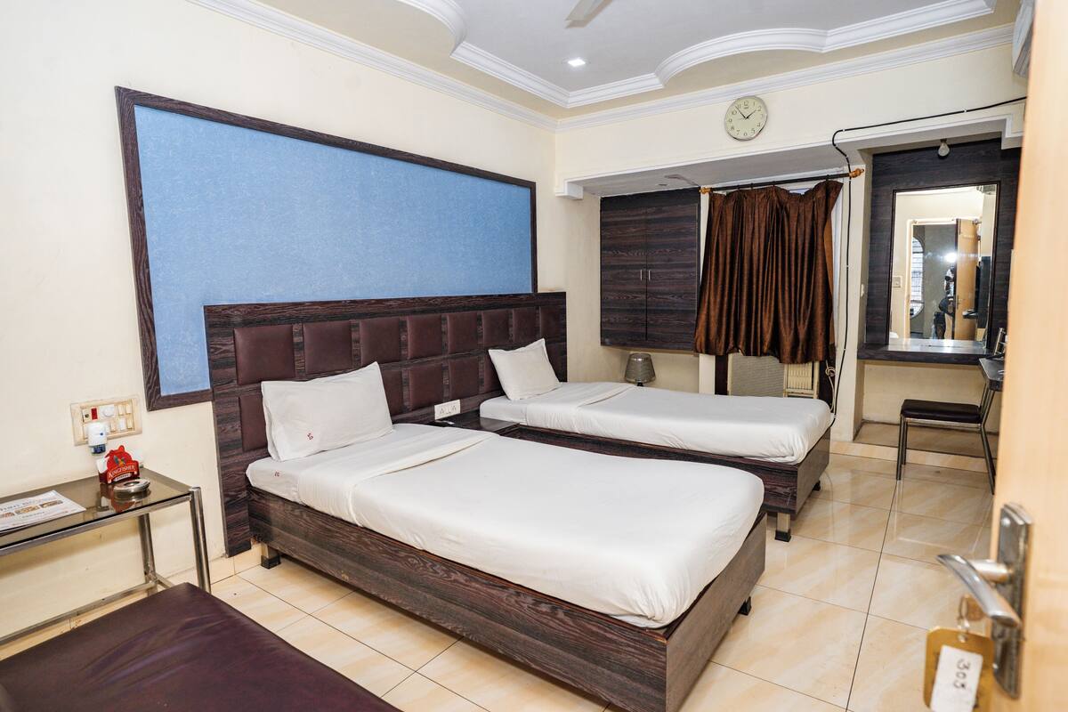 A hotel room with two beds, a desk, a chair, and a large window.