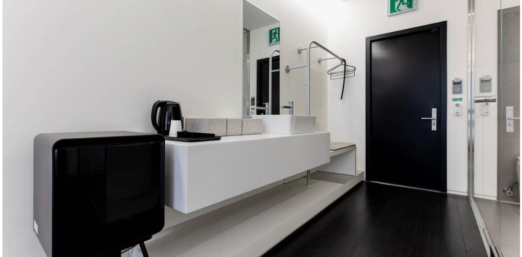 A modern bathroom with a large mirror, a black sink, and a black television.