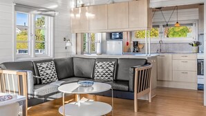 Una cocina moderna con horno empotrado, un comedor con mesa redonda y una zona de estar con sofá.