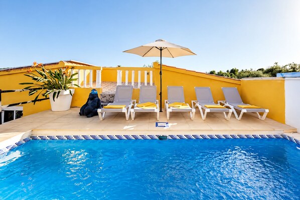 A swimming pool with lounge chairs and a potted plant.