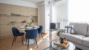 A modern kitchen with a dining area, a sofa, and a TV. - La Pergola 4B- Double Studio Exterior (Castellón)