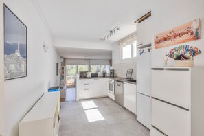 A modern kitchen with white cabinets, a microwave, oven, and dishwasher. There is a window providing natural light and a view of the outdoors.