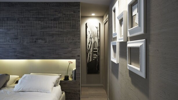 A modern bedroom with a large bed, a dark textured headboard, and a hallway with framed pictures on the wall. - Luxury Design Apartment Downtown - FREE PARKING (Milano)