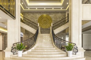 A grand staircase with a decorative ceiling medallion, marble steps, and potted plants. - MeliĆ” Vinpearl Hai Phong Rivera (Hai Phong Municipality)