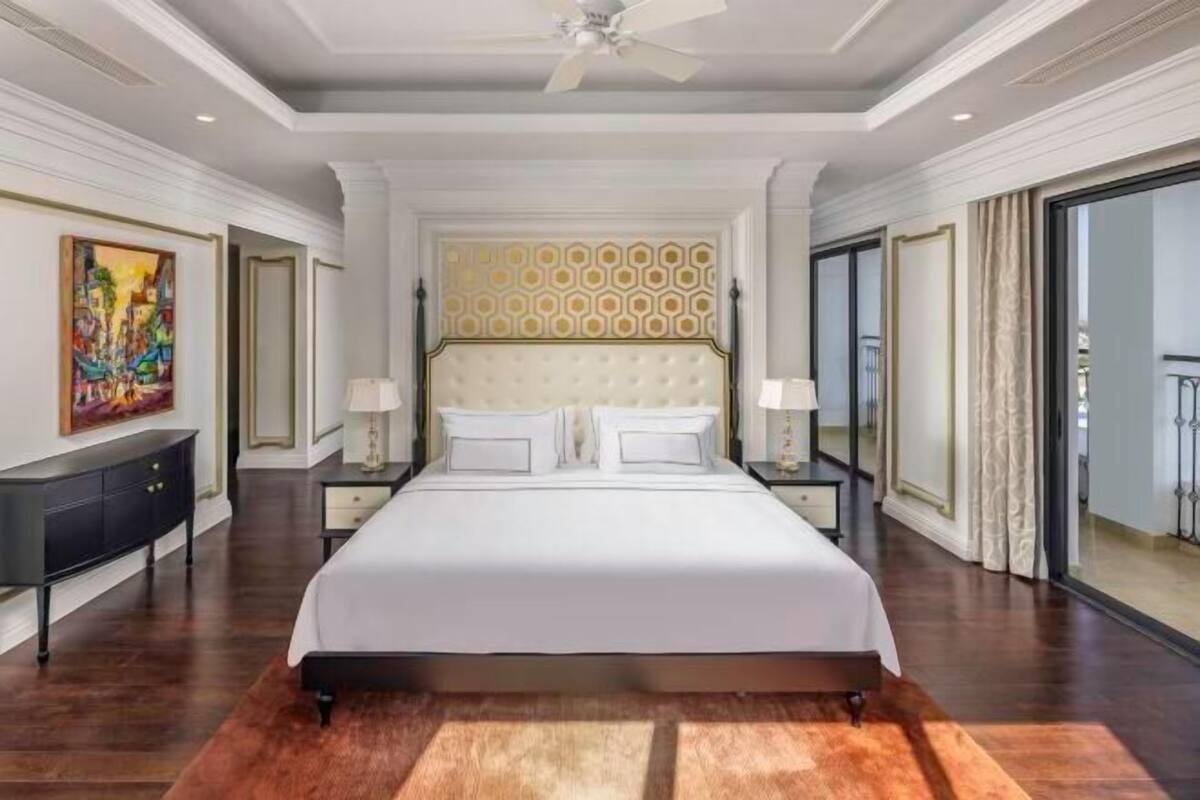 Um quarto espaçoso com uma cama grande, um ventilador de teto e um quadro na parede.
