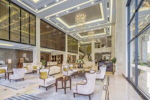 A spacious lobby with a grand staircase, plush seating, and a modern chandelier. - MeliĆ” Vinpearl Hai Phong Rivera (Hai Phong Municipality)