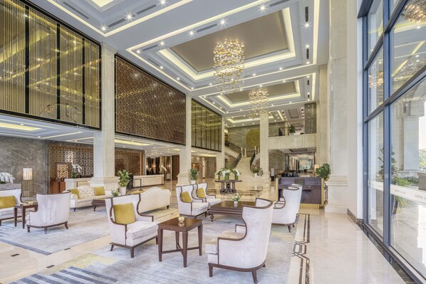 A spacious lobby with a grand staircase, plush seating, and a modern chandelier. - MeliĆ” Vinpearl Hai Phong Rivera (Hai Phong Municipality)
