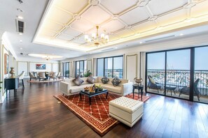 A spacious living room with a large sofa, a coffee table, and a balcony with a view. - Meliá Vinpearl Hai Phong Rivera (Hai Phong)
