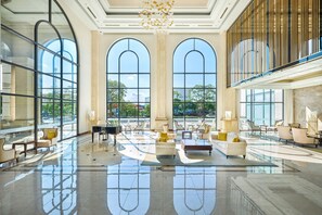 A spacious lobby with large arched windows, a chandelier, and modern furniture. - Meliá Vinpearl Hai Phong Rivera (Hai Phong)