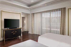 A hotel room with a large flat-screen TV on a black cabinet, a white bed, and a large window with sheer curtains. - MeliĆ” Vinpearl Hai Phong Rivera (Hai Phong Municipality)
