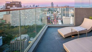 A balcony with wicker furniture and a city view.