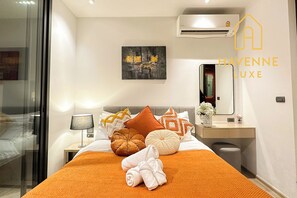 A hotel room with a bed, a bedside table with a lamp, a mirror, and a painting on the wall.
