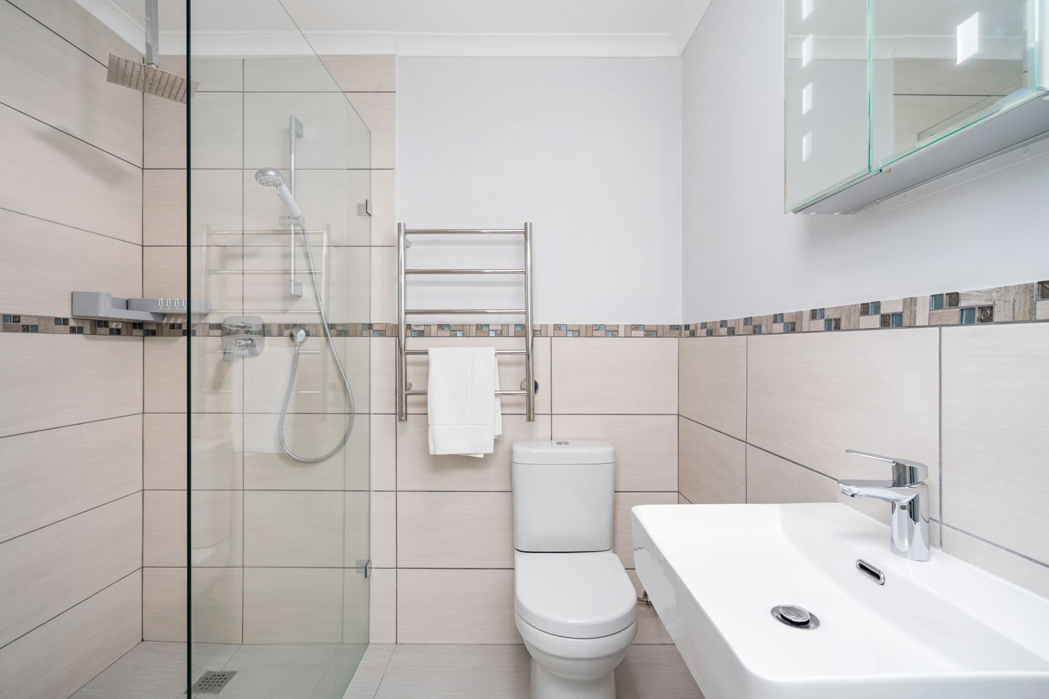 A modern bathroom with a glass shower enclosure, a white toilet, and a sink with a chrome faucet.