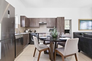 A modern kitchen with dark wood cabinets, stainless steel appliances, and a dining area with a round table and chairs. - Insignia 312 (Johannesburg)