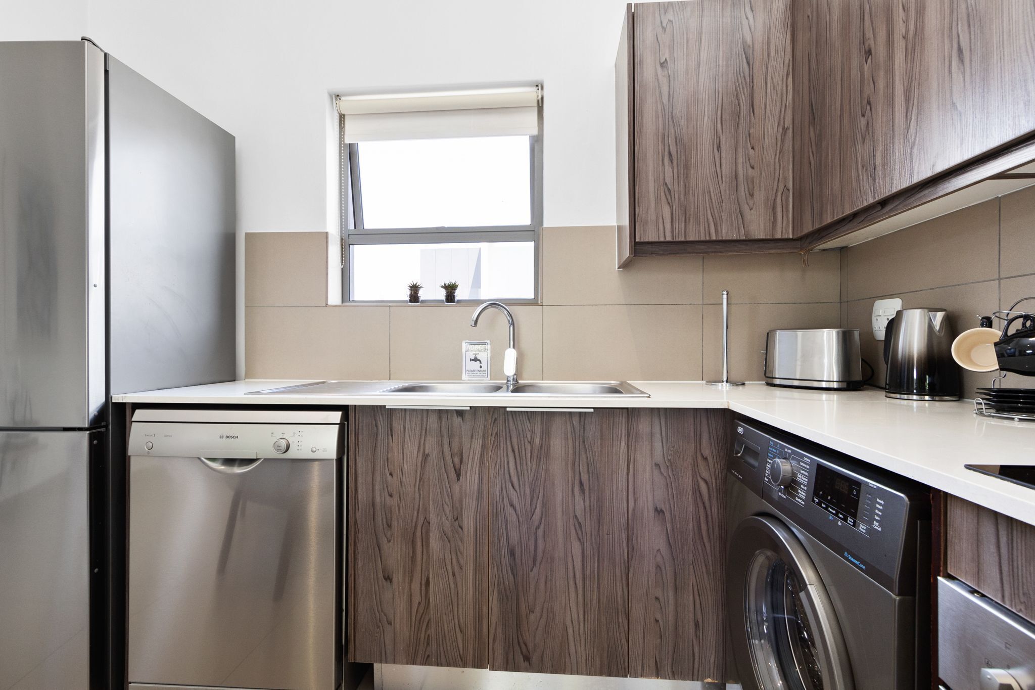 A modern kitchen with stainless steel appliances, a built-in dishwasher, and a washing machine.