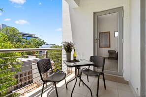 A balcony with a table, two chairs, a vase with flowers, and a bottle of wine. - Insignia 312 (Johannesburg)