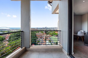 Un balcon avec vue sur la ville, un coin repas avec des chaises modernes et un sol en béton.