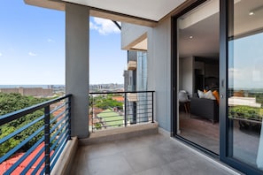 Un appartement moderne doté d’un balcon, de grandes fenêtres et offrant une vue sur le paysage urbain.