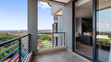 A modern apartment with a balcony, large windows, and a view of the cityscape.