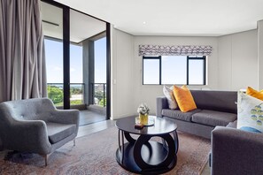 A modern living room with a grey sofa, a round coffee table, and a grey armchair.