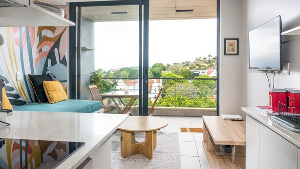 Un apartamento moderno con balcón, comedor y cocina.