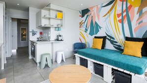 Un espacio habitable moderno y funcional, con kitchenette, comedor y sofá con espacio de almacenamiento.