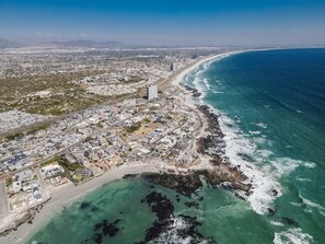 An aerial view of a coastal city with a beach, buildings, and a clear sky. - 17 Megan's Place (Cape Town)