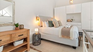 Une chambre à coucher moderne avec un lit, une table de chevet, une lampe et un miroir.