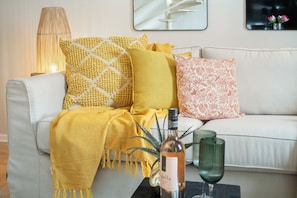 A living room with a sofa, decorative pillows, a lamp, a bottle, and a glass on a side table. - 104 Hideaway Loft Studio (Cape Town)