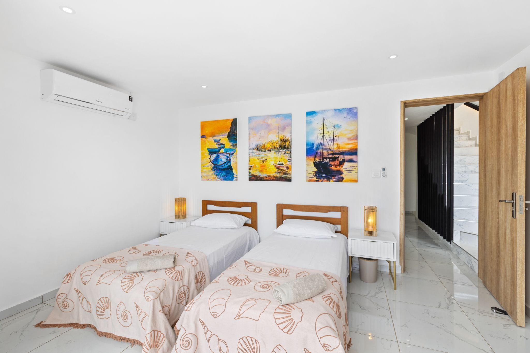Quarto de hotel com duas camas, uma janela grande e vista para o mar.