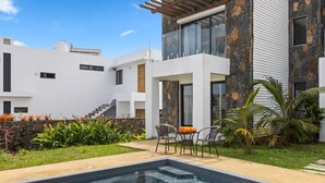 A modern house with a swimming pool, outdoor seating, and a stone facade. - 7 Green Village (Grand-Baie)
