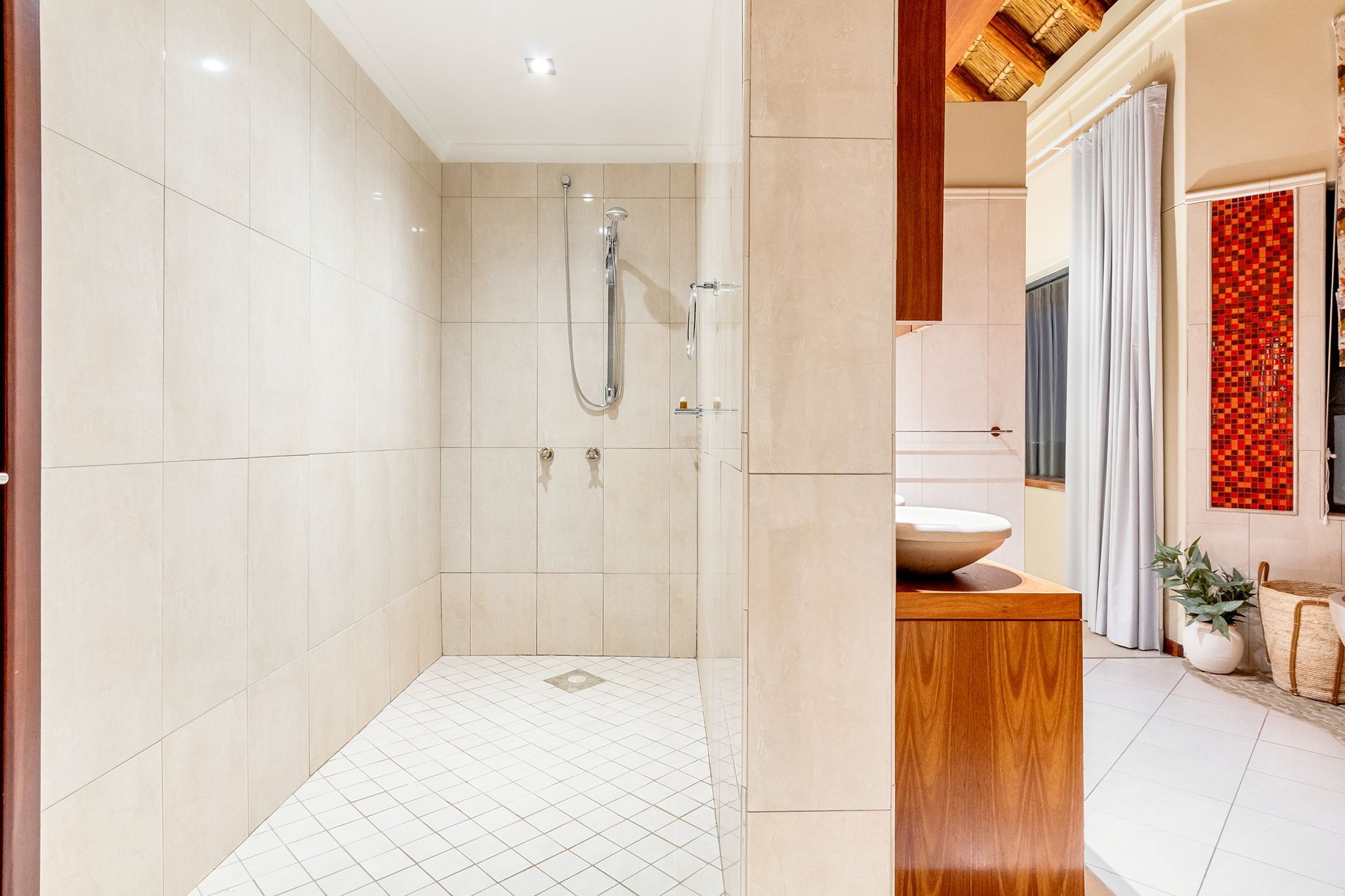 A modern bathroom with a walk-in shower, a wooden vanity, and a tiled floor.