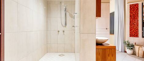 A modern bathroom with a walk-in shower, a wooden vanity, and a tiled floor.